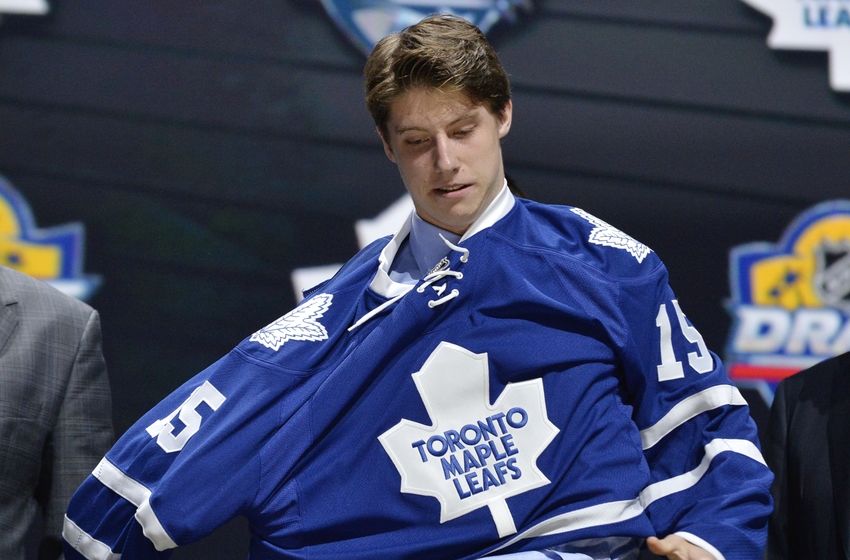 Jun 26, 2015; Sunrise, FL, USA; Mitchell Marner puts on a team jersey after being selected as the number four overall pick to the Toronto Maple Leafs in the first round of the 2015 NHL Draft at BB&T Center. Mandatory Credit: Steve Mitchell-USA TODAY Sports