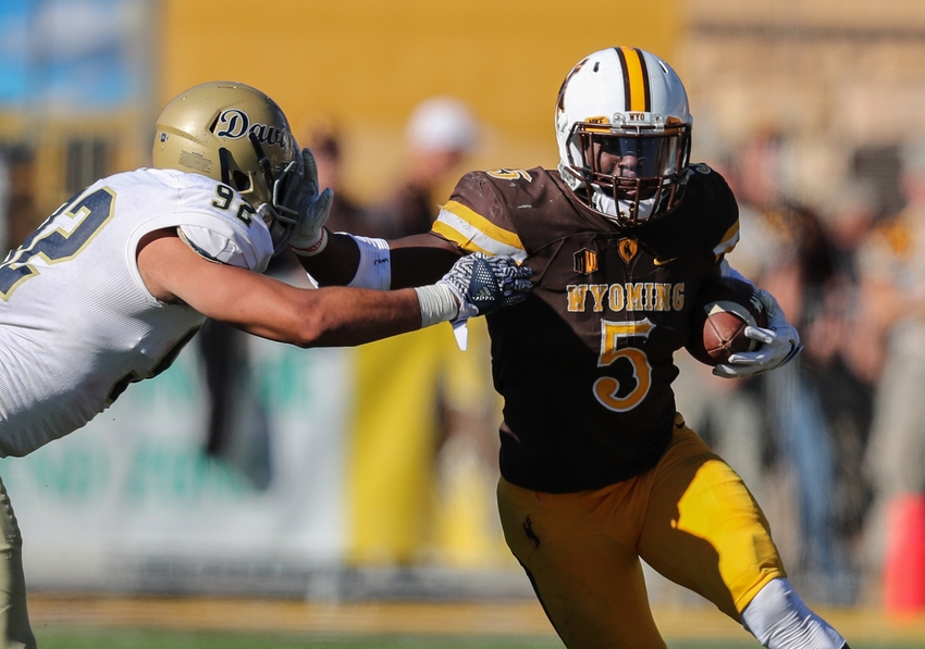 Wyoming Cowboys running back Brian Hill (5) carries the ball as UC Davis Aggies defensive lineman Anthony Baumgart (92) defends during the fourth quarter at War Memorial Stadium. The Cowboys won 45-22.