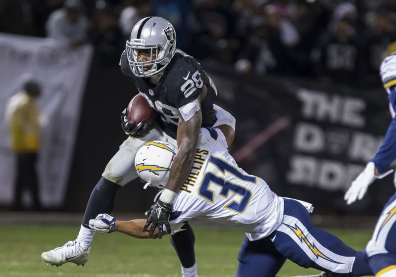Dec 24, 2015; Oakland, CA, USA; Oakland Raiders running back Latavius Murray (28) carries the ball against San Diego Chargers cornerback Adrian Phillips (31) during the third quarter at O.co Coliseum. The Oakland Raiders defeated the San Diego Chargers 23-20. Mandatory Credit: Kelley L Cox-USA TODAY Sports