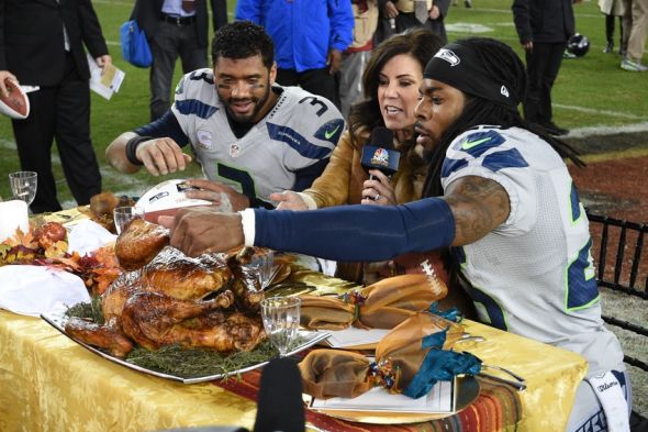 November 27, 2014; Santa Clara, CA, USA; Seattle Seahawks quarterback Russell Wilson (3) and cornerback Richard Sherman (25, right) reach for the turkey around NBC reporter Michele Tafoya (center) at Levi's Stadium. The Seahawks defeated the 49ers 19-3. Mandatory Credit: Kyle Terada-USA TODAY Sports