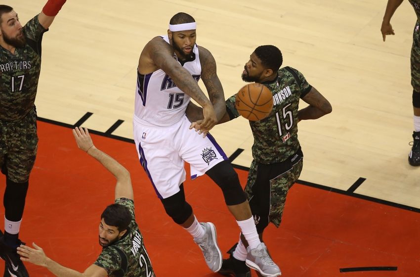 Jan 28, 2015; Toronto, Ontario, CAN; Sacramento Kings center DeMarcus Cousins (15) passes the ball under pressure from Toronto Raptors forward Amir Johnson (15) at Air Canada Centre. The Raptors beat the Kings 119-102. Mandatory Credit: Tom Szczerbowski-USA TODAY Sports