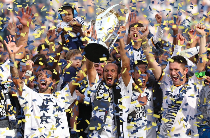 LOS ANGELES, CA - DECEMBER 07: (L-R) Juninho #19, Head Coach Bruce Arena, Landon Donovan #10, Marcelo Sarvas #8 and Robbie Keane #7 of the Los Angeles Galaxy celebrate on the podium with the Philip F. Anschutz Trophy after the Galaxy defeated the New England Revolution 2-1 in the 2014 MLS Cup at StubHub Center on December 7, 2014 in Los Angeles, California. (Photo by Victor Decolongon/Getty Images)